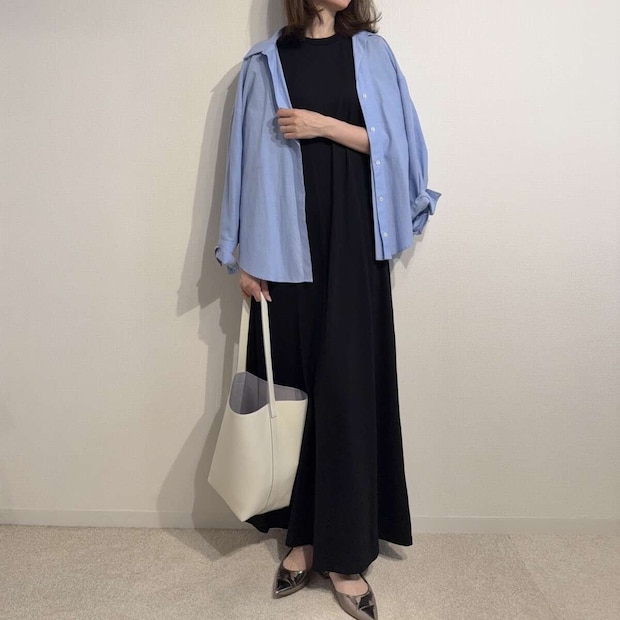 黒いワンピースに水色のシャツと白いバッグを合わせた女性の全身 黒いワンピースに水色のシャツと白いバッグを合わせた女性の全身