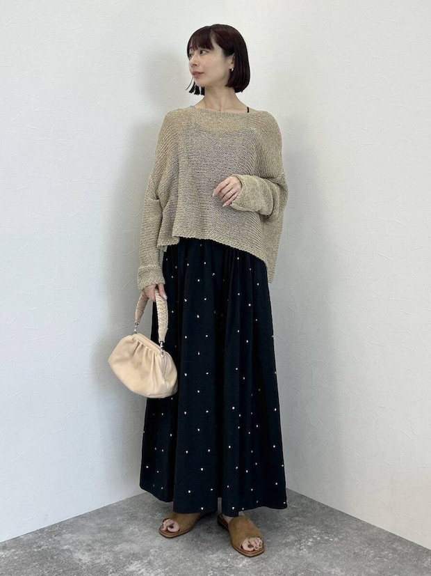 黒ドットワンピにベージュメッシュニットを重ねミニバッグを持つ女性 黒ドットワンピにベージュメッシュニットを重ねミニバッグを持つ女性