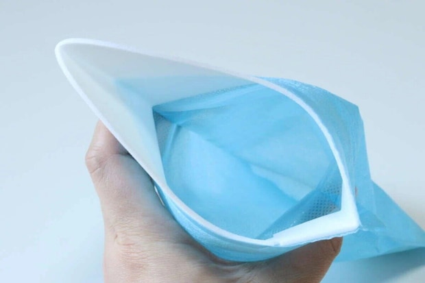 青い携帯できるトイレの開口部を広げて持っている手
