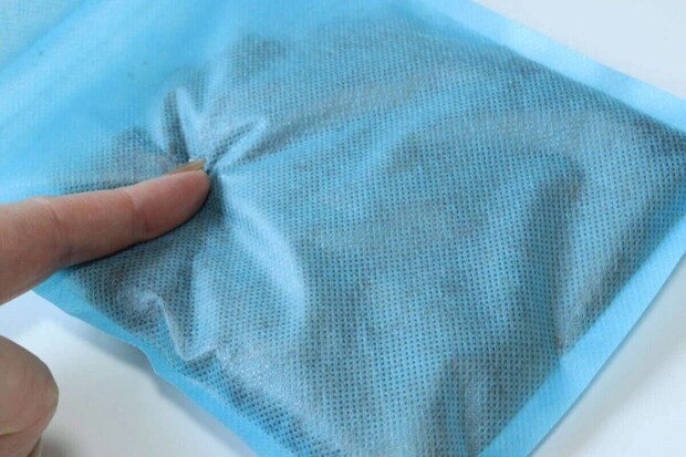 青い携帯できるトイレの吸水ポリマー部分を指で押している