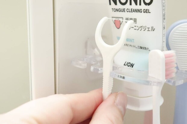 歯ブラシホルダーにY字フロスを引っ掛けている手元 歯ブラシホルダーにY字フロスを引っ掛けている手元