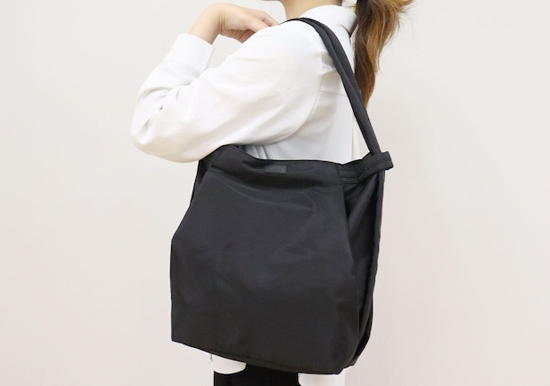 白シャツの女性が黒いバッグをトートとして肩掛け 白シャツの女性が黒いバッグをトートとして肩掛け