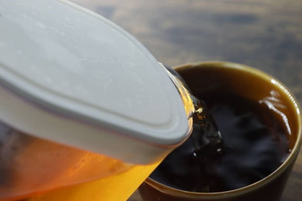 ピッチャーから茶色い飲み物をコップに注いでいる