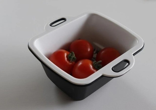 黒いバットと白いザルに赤いミニトマトが4つ入っている