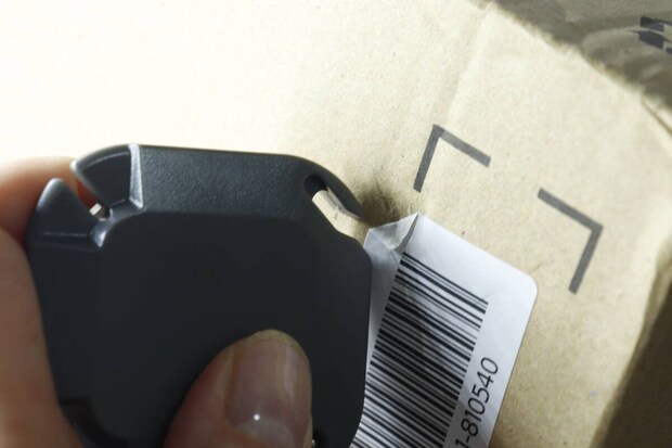 3WAY開封カッターで段ボールのラベルを剥がし始める手元