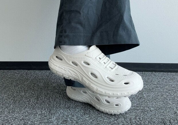 濃い色のパンツと白い靴下、白いEVAサンダルを履いた足元