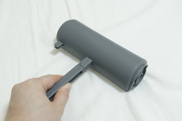 粘着テープをセットしたカーペットローラーで床を掃除する手
