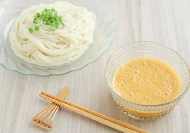 そうめんが盛られた皿と、納豆卵だれが入った器、箸