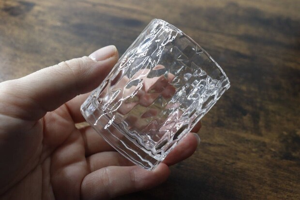 ダイヤモンドのような模様が特徴のミニグラスを片手で持っている様子 ダイヤモンドのような模様が特徴のミニグラスを片手で持っている様子