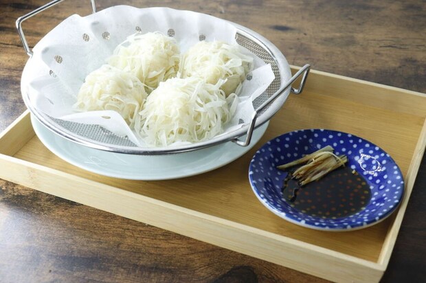 蒸し上がった焼売のような料理が浅型ザルに入り食卓に置かれている 蒸し上がった焼売のような料理が浅型ザルに入り食卓に置かれている