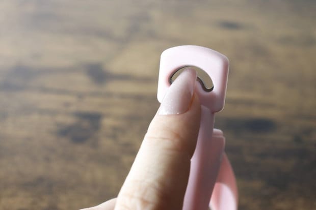 女性の指がネイルクリッパーの刃の穴に差し込まれている