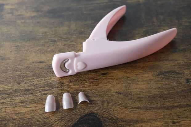 ピンク色のネイルクリッパーとカット済みのネイルチップ3つ