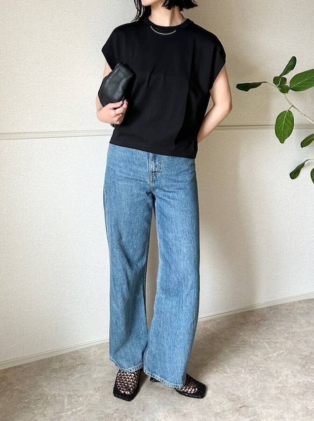 黒いTシャツとデニムのシンプルなNGコーデで、女性がバッグを持っている