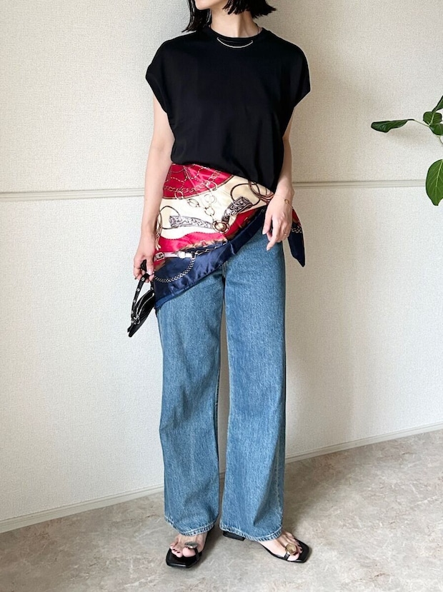 黒いTシャツとデニムにスカーフを腰巻きしたOKコーデの女性