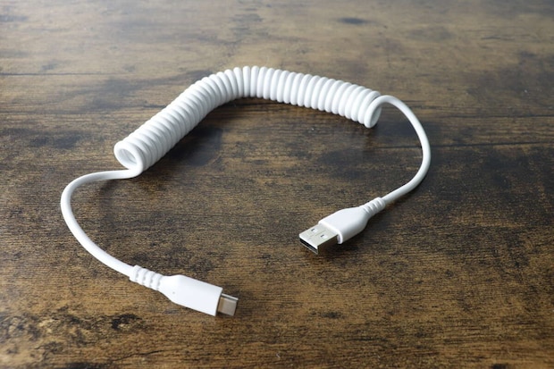 木目調のテーブルに置かれた白いコイル状のType-Cケーブル