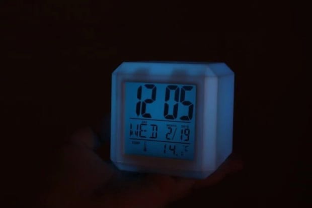 暗闇で青く光るデジタル時計が時刻、日付、曜日、温度を表示