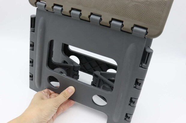 折りたたみイスの脚をたたむ動作をしている手元