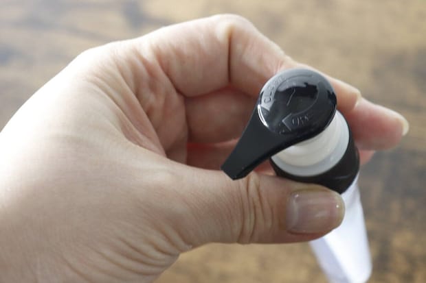 ポンプヘッドのロック機能部分を女性の指で示している