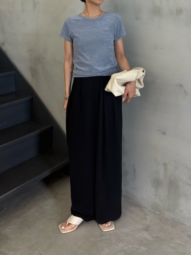 グレイッシュブルーTシャツと黒ワイドパンツの女性が白いバッグを持つ