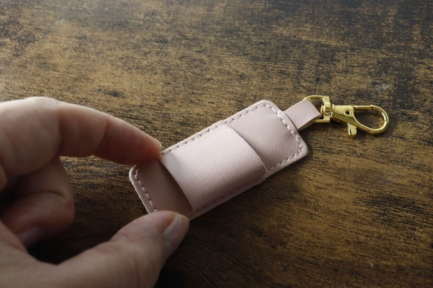 女性の指がピンクのペンホルダーのベルト部分を押している