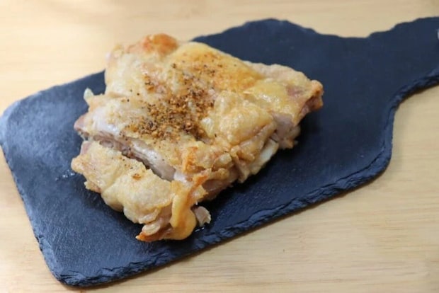 黒いスレートプレートに鶏肉のグリルが盛り付けられている