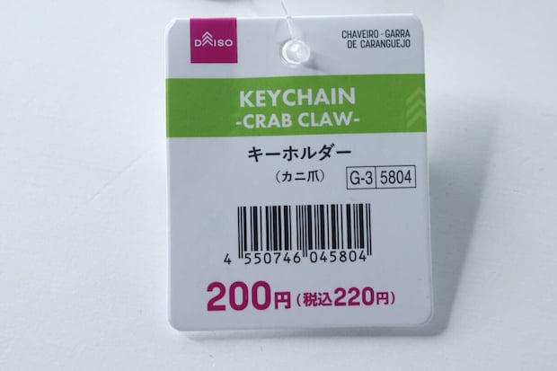 ダイソーのカニ爪キーホルダーの商品タグのアップ。価格とJANコードが見える ダイソーのカニ爪キーホルダーの商品タグのアップ。価格とJANコードが見える