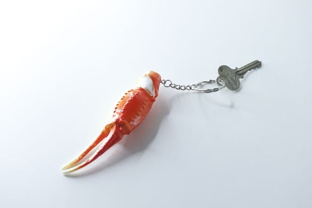 白い背景に置かれた、鍵が取り付けられたカニ爪キーホルダー