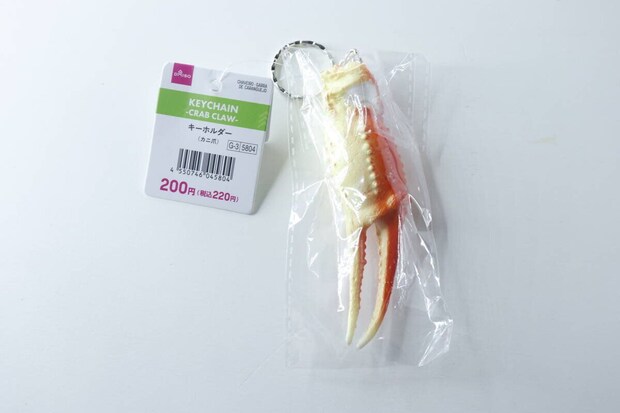 透明な袋に入ったダイソーのカニ爪キーホルダーと商品タグ 透明な袋に入ったダイソーのカニ爪キーホルダーと商品タグ