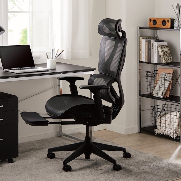 黒いメッシュ素材のオフィスチェアがデスクと棚のある部屋に置かれている 黒いメッシュ素材のオフィスチェアがデスクと棚のある部屋に置かれている