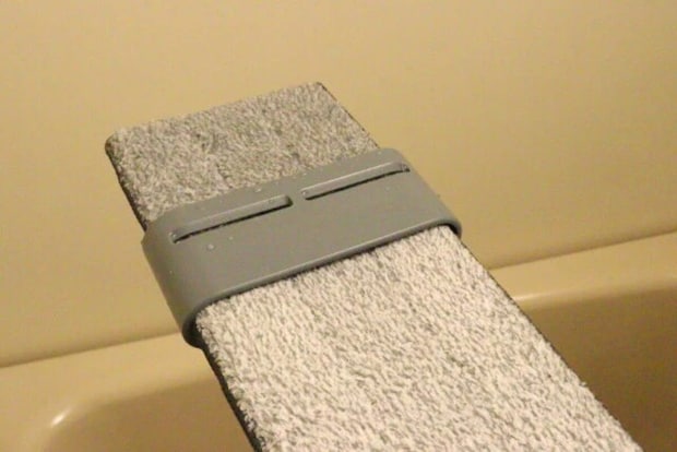 グレーのモップヘッドがバケツの縁に押し付けられ水絞りされている様子 グレーのモップヘッドがバケツの縁に押し付けられ水絞りされている様子