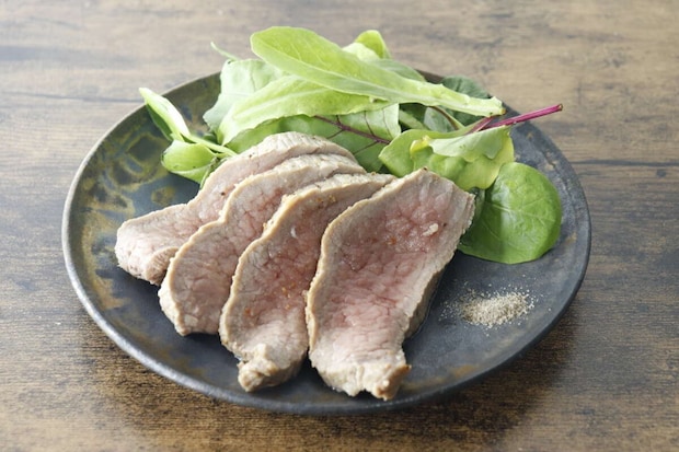 スライスされた肉とサラダが盛られた皿の横に燻製塩こしょうが添えられている スライスされた肉とサラダが盛られた皿の横に燻製塩こしょうが添えられている