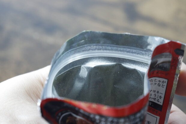 手で持たれた「PattoDELI 燻製塩こしょう」のチャック付き袋の開口部 手で持たれた「PattoDELI 燻製塩こしょう」のチャック付き袋の開口部