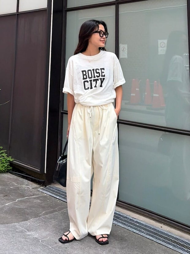 黒縁メガネの女性が白Tシャツと白バレルパンツで立つ全身 黒縁メガネの女性が白Tシャツと白バレルパンツで立つ全身