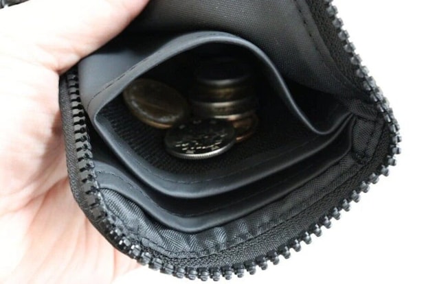 黒いL字型財布の開いた小銭入れに硬貨が見える 黒いL字型財布の開いた小銭入れに硬貨が見える