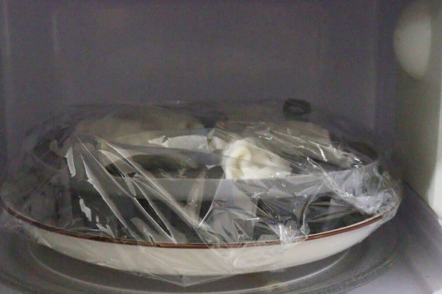 電子レンジの中でラップをかけた皿に蒸し器が入っている様子 電子レンジの中でラップをかけた皿に蒸し器が入っている様子