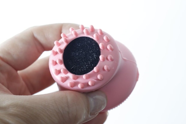 女性の手に持たれた洗顔ブラシの底面。黒いスポンジと突起が見える 女性の手に持たれた洗顔ブラシの底面。黒いスポンジと突起が見える