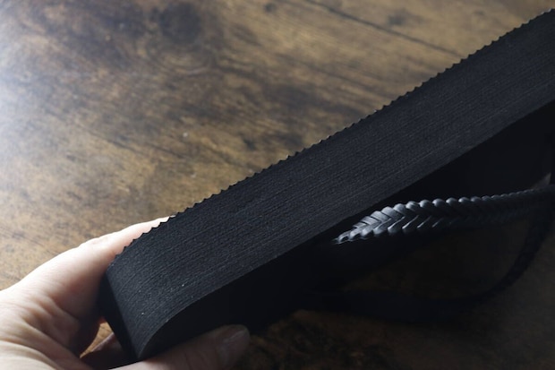 手で持った黒い厚底ビーチサンダルの分厚いソール部分を横から撮影 手で持った黒い厚底ビーチサンダルの分厚いソール部分を横から撮影