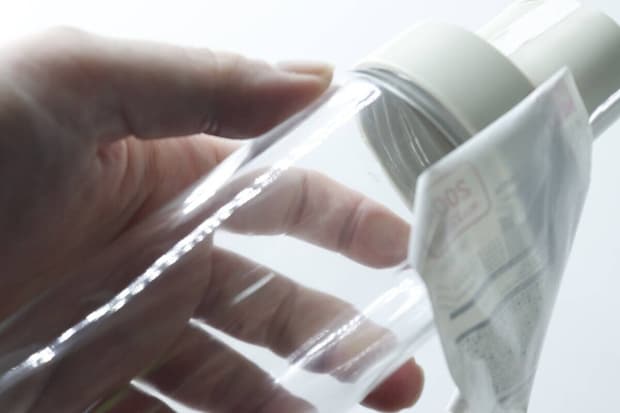 オイルボトルから商品ラベルを剥がしている手のアップ
