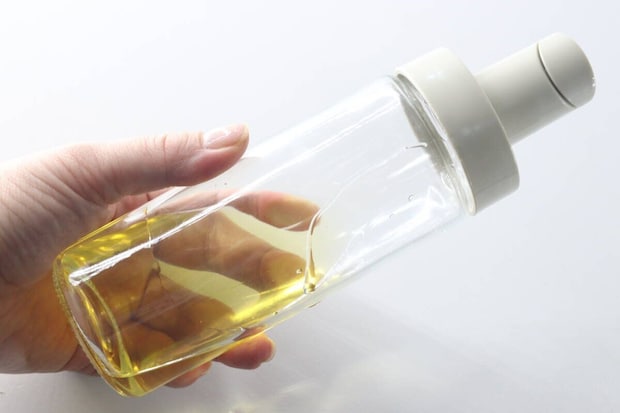 食用油が入ったオイルボトルを手に持ち、残量を確認している