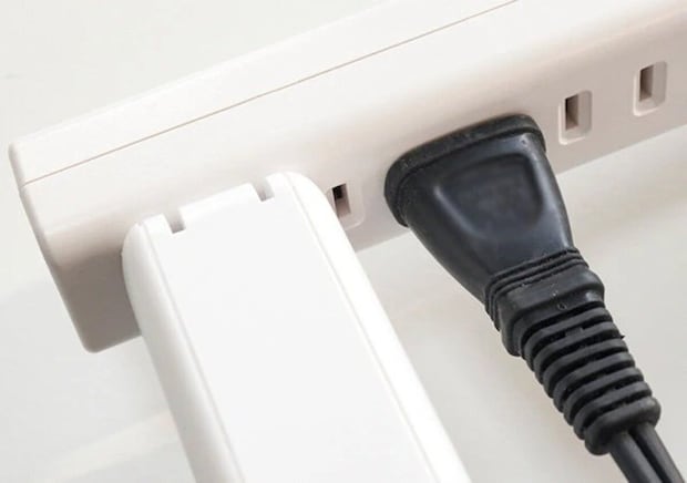 白い延長コードに大きなアダプターと黒いプラグが挿さっている 白い延長コードに大きなアダプターと黒いプラグが挿さっている