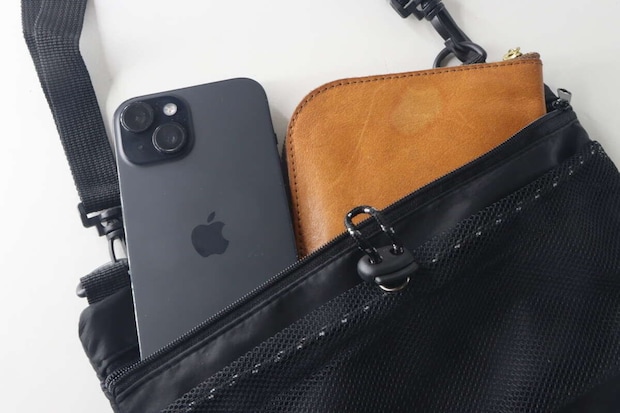 黒いショルダーバッグのフロントポケットにスマホと財布が入っている
