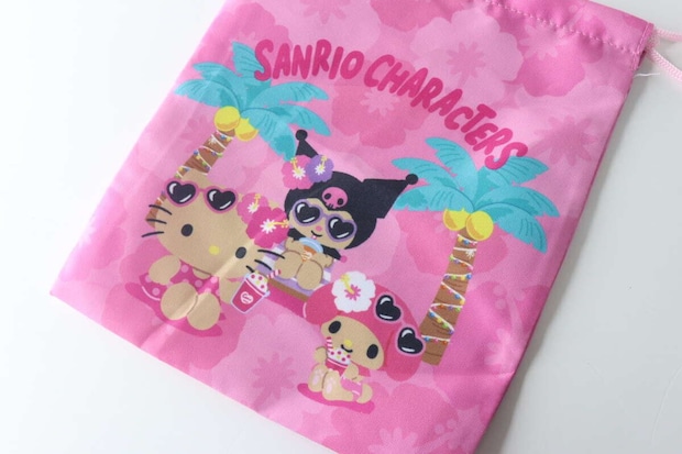 ピンク色の巾着袋の表面に描かれた、日焼けしたキティ、マイメロ、クロミのキャラクターデザインのアップ