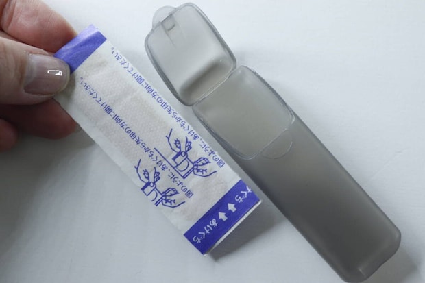 絆創膏のパッケージと開いたグレーのトラベル小物ケース