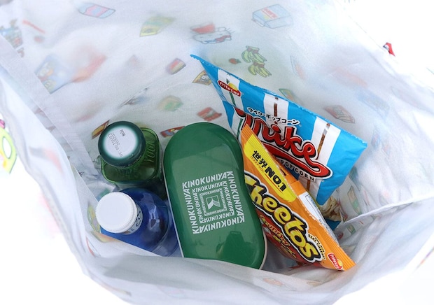 白地の保冷・保温バッグの中に、ペットボトルや弁当箱、スナック菓子などが入っている様子