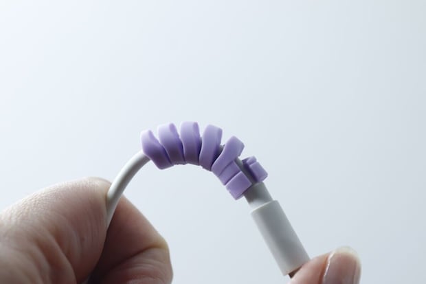 紫のプロテクターを装着した白い充電ケーブルを曲げている様子