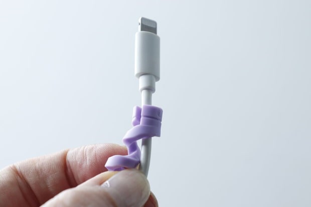 白い充電ケーブルの根元に紫のプロテクターを装着し始めた様子