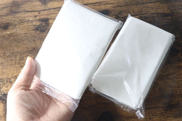 手のひらにコンパクトに畳まれたレジ袋の束が2つ乗っている 手のひらにコンパクトに畳まれたレジ袋の束が2つ乗っている