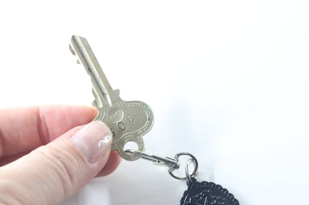 キーホルダーの金具に鍵を取り付けている手元をクローズアップ