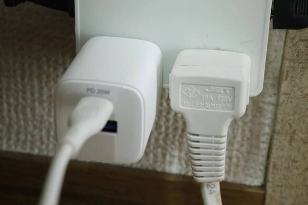白い充電器がコンセントに挿され隣のプラグと並んでいる 白い充電器がコンセントに挿され隣のプラグと並んでいる
