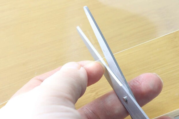 ハサミで透明な粘着ゲルシートをカットしている手元 ハサミで透明な粘着ゲルシートをカットしている手元